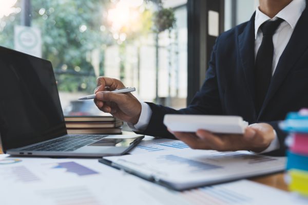 Asian businessman working in the office, calculating financial reports, organizing paperwork using a laptop and calculator as an aid.management concept accounting.